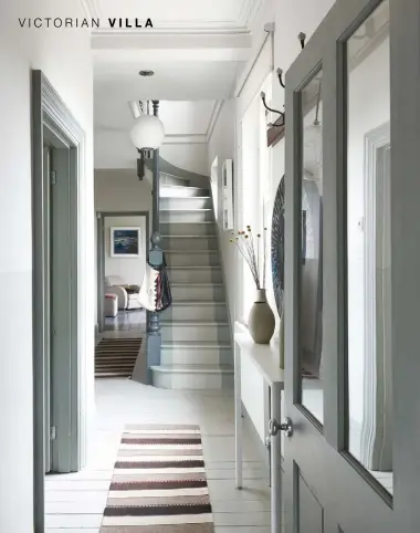  ??  ?? ENTRANCE HALL Wooden floors painted in Strong White, doors and architrave in Pigeon, balustrade in Downpipe Grey, and walls in Shaded White, Hardwick White and Slipper Satin, all Farrow &amp; Ball, create a striking entrance. The slim console table is from Spanish brand Santa &amp; Cole, available from Momentum, and the rugs are from Ikea