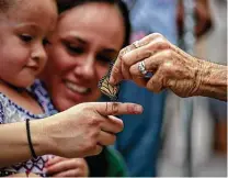  ?? Josie Norris / Staff file photo ?? Monika Maeckle places a tagged monarch butterfly on the finger of Victoria Martinez at last year’s festival.