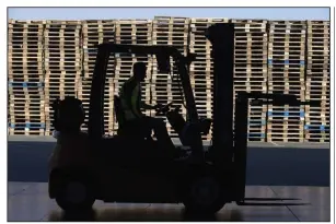  ?? (Bloomberg/Andrew Caballero-Reynolds) ?? A worker drives a forklift past stacked wooden pallets.