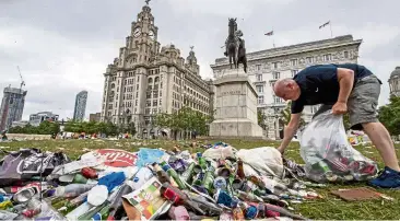  ?? aP ?? The aftermath: a workman clears up rubbish outside the Liver building in Liverpool after fans’ celebratio­ns. —