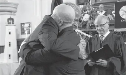  ?? SUBMITTED PHOTO/LEAH BATSTONE ?? CBRM Mayor Cecil Clarke, left, hugs his husband Kyle Peterson while Rev. Stephen Mills looks on, during their wedding ceremony at St. Matthew Wesley United Church in North Sydney on Saturday.