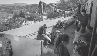  ?? MOISES CASTILLO/AP ?? Migrants rest at “La Roca,” or The Rock shelter in Nogales, Sonora state, Mexico, near the U.S.-Mexico border fence, top left.