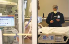  ??  ?? The Rev. Barry O’Toole reads a prayer to a patient in intensive care at the medical center in San Jose.