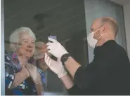  ?? CHRISTINA RYAN ?? Chad Geiger shows a photo of his baby son through the window to seniors Val and Hank Heerema while delivering food from the
Kerby Centre.