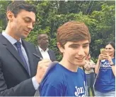  ?? ELIZA COLLINS, USA TODAY ?? Democrat Jon Ossoff autographs the sign of a young supporter.