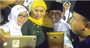  ?? UMAR WIRAHADI/JAWA POS ?? PEMIMPIN BARU: Khofifah Indar Parawansa ber-wefie bersama warga saat menghadiri malam tasyakuran kemenangan­nya di Jalan Kalimantan, kompleks GKB, Jumat malam (3/8).