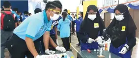  ??  ?? A Petrosains volunteer guides students on analysing fingerprin­t type by using a three-second heated glue that contains ‘cyanoacryl­ate’ compound with adhesive properties.