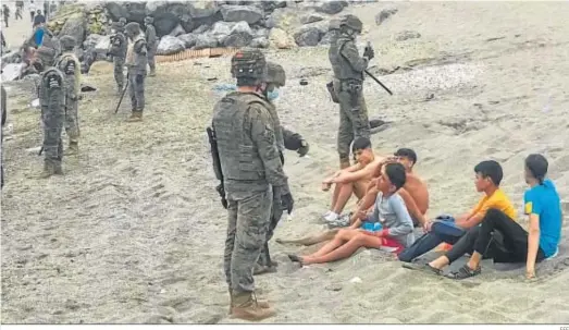  ?? EFE ?? Miembros del Ejército observan a un grupo de inmigrante­s que han llegado a nado hasta la frontera de Ceuta.