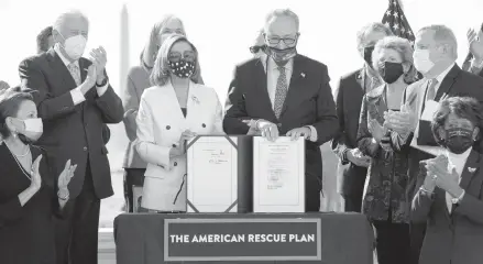  ?? OLIVIER DOULIERY/GETTY-AFP ?? Speaker of the House Nancy Pelosi and Senate Majority Leader Chuck Schumer display the American Rescue Plan Act on Wednesday after the House approved final legislatio­n for the $1.9 trillion relief package.