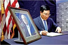  ?? — Reuters photo ?? Minh writes in a condolence book near a portrait of McCain at the US embassy in Hanoi.