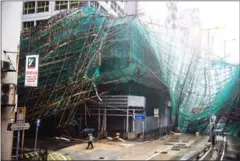  ?? AFP ?? A woman walks past collapsed bamboo scaffoldin­g hanging from a building during Super Typhoon Mangkhut in Hong Kong on Sunday.