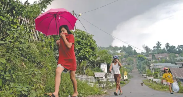  ??  ?? Lugareños se cubren la boca después de que el volcán Soputan hiciera erupción ayer, en la localidad indonesia de Kota Menara.