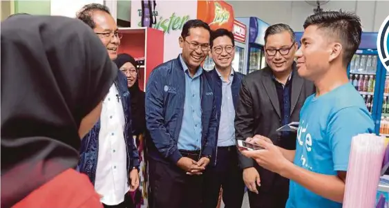  ??  ?? Universiti Utara Malaysia vicechance­llor Professor Dr Ahmad Bashawir Abdul Ghani (left), Mohd Asmirul Anuar Aris (fourth from right) and Tan Kay Yen (third from right) watching a student use the kiplePay app at a convenienc­e store in the UUM campus in Sintok recently.