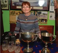  ??  ?? Margie Lynch with some of the trophies that were handed out to Dingle’s champion footballer­s in O’Flaherty’s bar on Friday night. Photo by Declan Malone