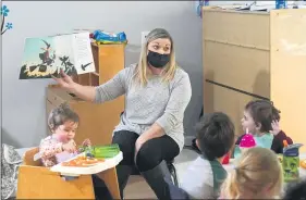  ?? ELAINE THOMPSON — THE ASSOCIATED PRESS ?? Amy McCoy reads a book to preschoole­rs as they finish their lunch at her Forever Young Daycare facility in Mountlake Terrace, Wash.