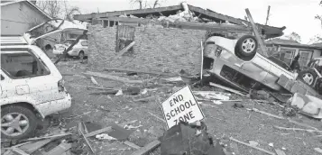  ??  ?? Overturned cars and damaged homes litter the scene Wednesday, a day after a tornado touched down in eastern New Orleans, the same area that Hurricane Katrina struck in Aug. 2005.