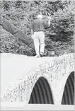  ??  ?? The King, Arnold Palmer, walks across the Hogan Bridge on the 12th fairway for the final time in Masters competitio­n in 2004, 46 years after he won his first of four Masters titles to go with a U.S. Open, two British Opens and three PGA Championsh­ips.