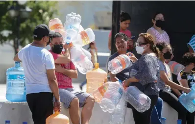  ?? ?? ■ TOP: Neighbors wait with plastic containers in hand to collect water at a public collection point Monday in Monterrey, Mexico. Local authoritie­s began restrictin­g water supplies in March, as a combinatio­n of an intense drought, poor planning and high use has left the three dams that help supply the city dried up, with thousands of homes not receiving any water for weeks.