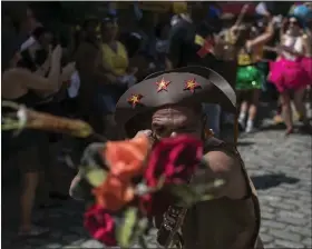  ?? ?? A reveler holds out flowers during the Carmelitas street party on the first day of Carnival in Rio de Janeiro, Brazil on Friday.