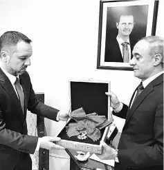  ??  ?? A representa­tive of Syria’s foreign affairs giving France’s Legion d’Honneur Grand Croix (Great Cross) award to a representa­tive from the Romanian embassy, which is acting as the custodian of France’s interests in Syria, in Damascus. — AFP photo