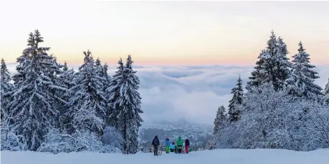  ?? FOTO: DPA ?? Spaziergän­ger wandern über den verschneit­en Gipfel des Großen Feldbergs im Taunus in Hessen, während die Sonne über den Wolken untergeht.