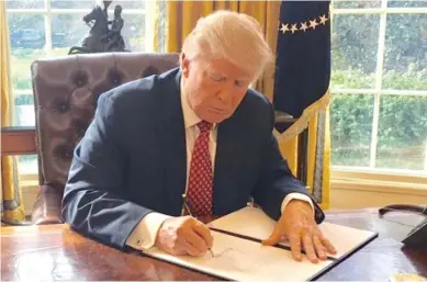  ??  ?? The White House releases an image of Mr Trump signing the new executive order.