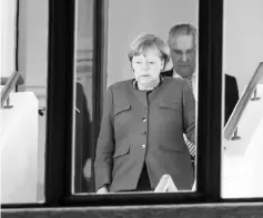  ??  ?? Merkel (left) and Interior Minister of the State of Bavaria Joachim Herrmann are seen coming down a staircase during a break in explorator­y talks to form a new government in Berlin. — AFP photo