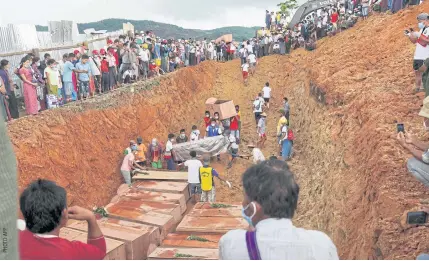  ??  ?? FINAL RESTING PLACE: People bury bodies of miners in a mass grave while relatives look on during a funeral ceremony near Hpakant in Kachin State on Friday.