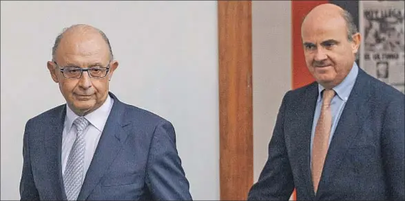  ??  ?? Cristóbal Montoro, ministro de Hacienda, y Luis de Guindos, de Economía, han diseñado una tasa para la banca con el fin de evitar sanciones