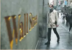  ?? (Lucas Jackson/Reuters) ?? A MAN wears a protective mask as he walks on Wall Street during the coronaviru­s outbreak in New York City earlier this month.