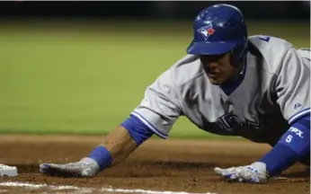  ?? DAVID GOLDMAN/THE ASSOCIATED PRESS ?? Jays baserunner Yunel Escobar dives back to first early on against the Braves, who finally won in the 10th inning.