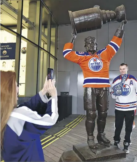  ?? ED KAISER ?? Joseph Foisy gets his picture taken Tuesday by his mom Christine next to the Wayne Gretzky statue outside Rogers Place. Someone dressed the statue in an Oilers jersey.