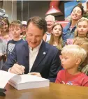  ?? STEVE HELBER/AP ?? Gov. Glenn Youngkin signs the budget at a ceremony at a grocery store Tuesday in Richmond.