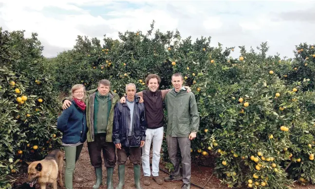  ?? Fotos: dpa ?? Jung-Landwirt Gonzalo Úculo (Zweiter von rechts) mit einem Teil seines internatio­nalen Teams vor den Orangenbäu­men seiner Plantage.