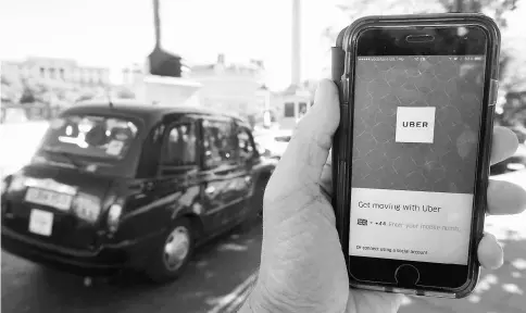  ??  ?? A photo illustrati­on shows a London taxi passing as the Uber app logo is displayed on a mobile telephone in central London Sept 22. Last month, the London transit authority dropped a bombshell. It was not going to renew Uber’s five-year-old licence, it...