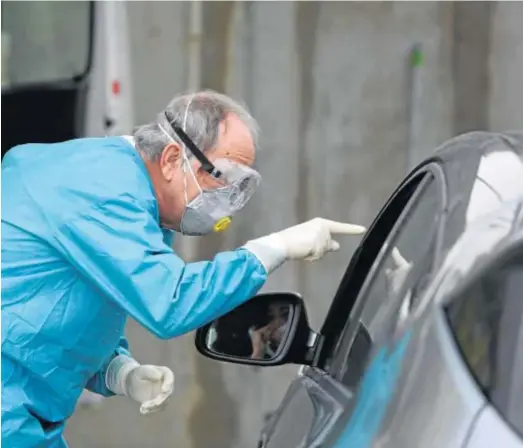  ?? JAVIER ALBIÑANA ?? Un sanitario toma una muestra a un sospechoso de estar infectado de coronaviru­s.