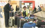  ?? Jessica McGowan / Getty Images ?? David Walker (left) searches for his luggage at Hartsfield-Jackson Atlanta Internatio­nal Airport.