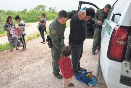  ?? COURTNEY SACCO/USA TODAY NETWORK ?? Lester Morales, 27, of Guatemala is patted down by a U.S. Border Patrol agent after he was intercepte­d this week near McAllen, Texas. He says he was separated from his wife and daughter during his journey and now fears losing his son.