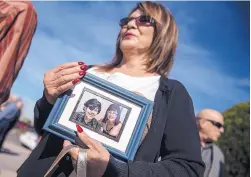  ??  ?? Diana Charles, a longtime fan of the late music legend Al Hurricane, carries a photo of him outside Queen of Heaven Church after a funeral Mass on Monday. She said the photo was taken about a year ago after a performanc­e.