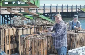  ?? ERIC MCCARTHY/JOURNAL PIONEER ?? Crew member Garrett Aylward, right, gets a hand from volunteer Mike King in offloading lobster traps from Jamie Aylward’s vessel Thursday morning in Tignish. Thursday was the last day of the spring fishery, landing day, and the wharf quickly filled up...