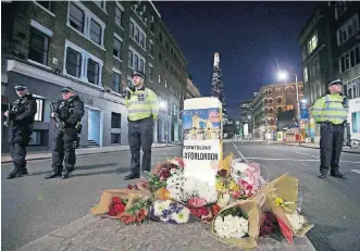  ?? [AP PHOTO] ?? Police officers on duty stand next to floral tributes on Southwark Street in London on Sunday near the scene of Saturday’s attack.