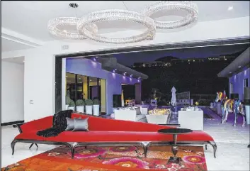  ??  ?? A 20-foot-long, deep-red chaise lounge stretches under three ring-shaped crystal chandelier­s in the entry of the home.