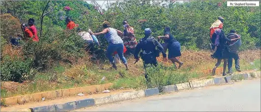  ?? Pic: Shepherd Tozvireva ?? Commuters scurry for cover after riot police officers use batons to disperse them at the flyover bus stop along Simon Mazorodze Road in Harare yesterday