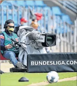  ??  ?? Uno de los cámaras de televisión de la Bundesliga con mascarilla.