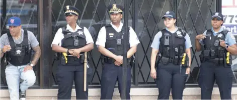  ?? COLIN BOYLE/SUN-TIMES ?? Chicago police officers stand across 71st Street from Jeffrey Plaza the day after the shooting of Harith Augustus on July 15.