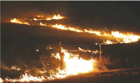  ?? [AP PHOTO] ?? Wildfires swept by high winds burn near Protection, Kansas, early Tuesday. Firefighte­rs in Oklahoma and Kansas were battling wildfires Tuesday.