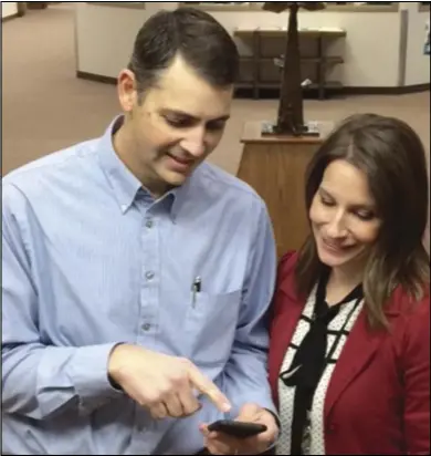  ??  ?? David Taylor demonstrat­es how the new Family Nexus app works on an iPhone to Michele Child in Springvill­e. The free app helps users visualize the places where ancestors were from and brings new discoverie­s about family right to the phone.