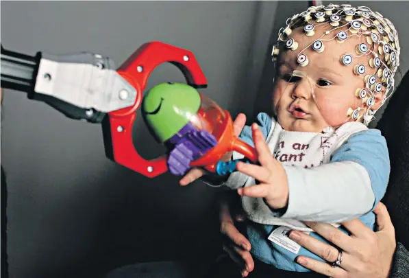  ??  ?? Thomas Crabtree, 8 months, wears an EEG net to monitor his brain activity during an experiment at the Babylab at Birkbeck University, London. which studies how babies learn and develop