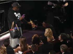  ?? PHOTO BY CHRIS PIZZELLO — INVISION — AP ?? Mahershala Ali, right, hands his award for best actor in a supporting role for “Moonlight” to a tourist named Gary during the Oscars on Sunday at the Dolby Theatre in Los Angeles.