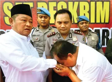  ?? BOY SLAMET/JAWA POS ?? BEBAS DARI JERAT HUKUM: Nur Slamet mencium tangan usai Bupati Sidoarjo Saiful Ilah mencabut laporan di Mapolresta Sidoarjo kemarin.